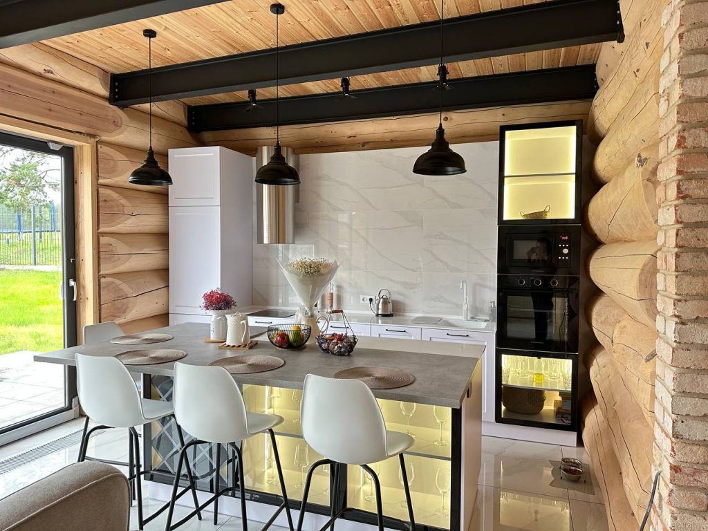 Дизайн кухни-гостиной в деревянном доме из сруба с элементами лофта: кухонный остров, черные металлические балки и современная техника. Пример нашей отделки под ключ в г. Томск.